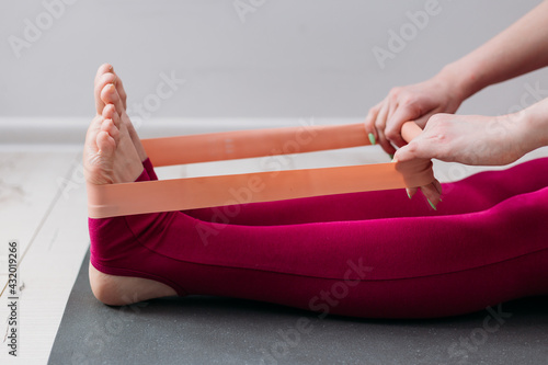 Resistance band exercise at home. Woman doing pilates workout using elastic  strap pulling with arms for shoulder training on yoga mat indoors. Sport  and healthy active lifestyle concept. Stock Photo