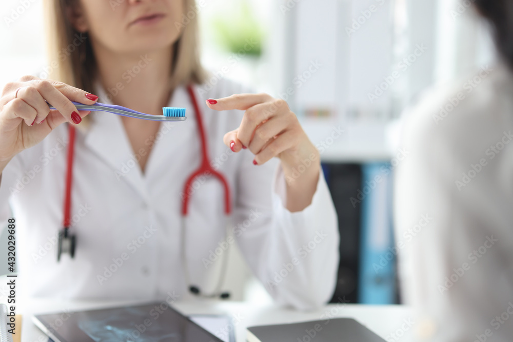 Doctor shows the toothbrush to patient closeup Doctor shows the toothbrush to patient closeup