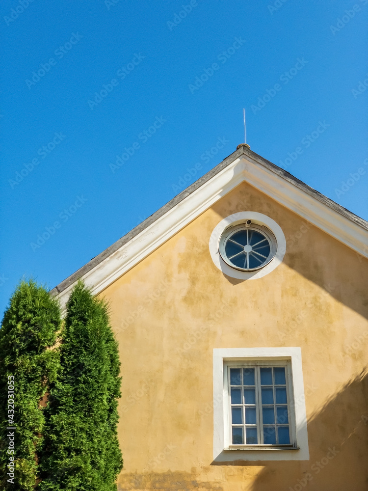 yellow facade of building with cypress tree white windows and blue sky