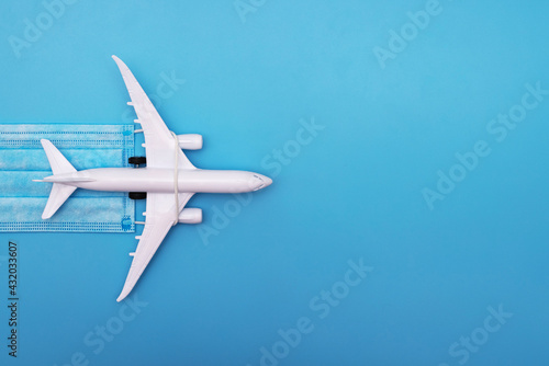 Wallpaper Mural A plane model with a medical mask on a blue background. Safety flight and travel during quarantine and lockdown. Safe travels concept. Opening borders Torontodigital.ca
