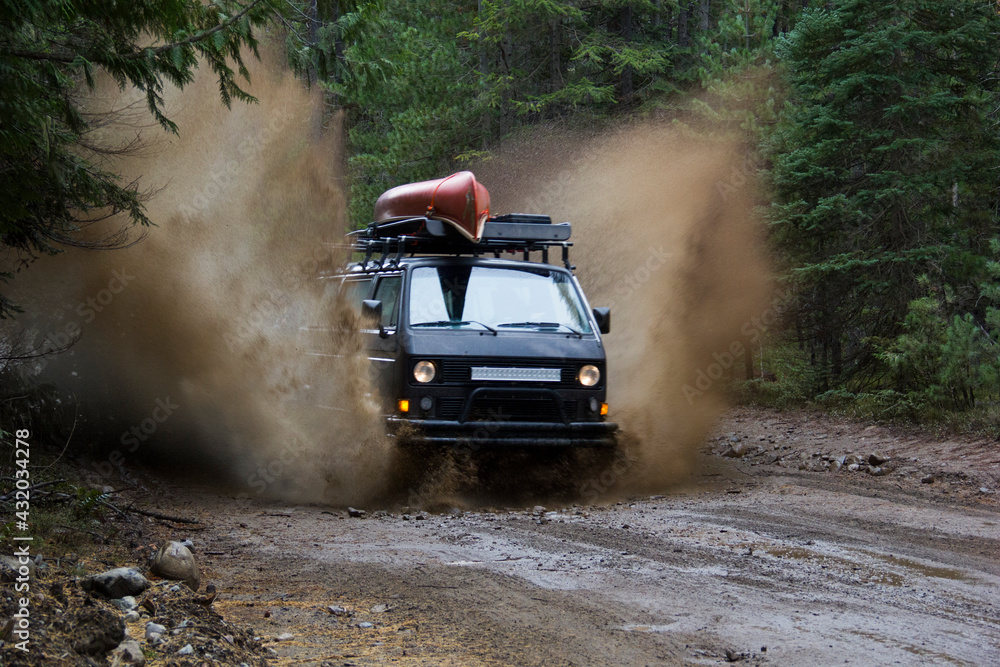 A Volkswagen Synchro van charges through a mud puddle on a dirt back road. A Volkswagen Synchro van charges through a mud puddle on a dirt back road.