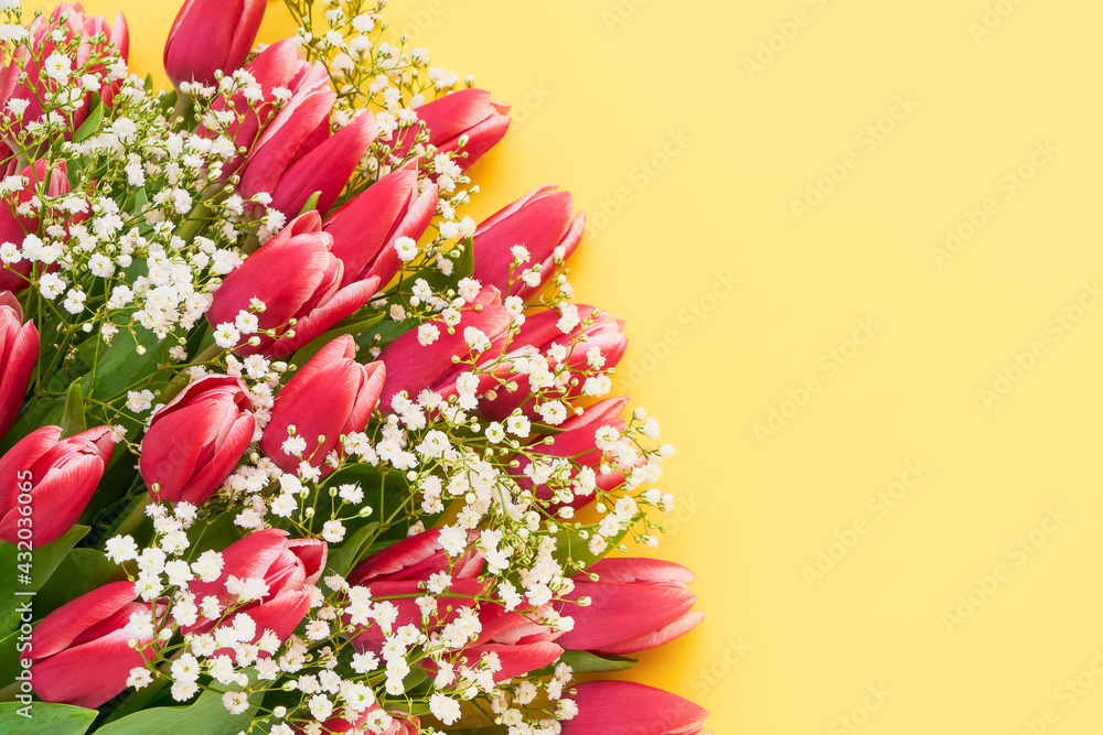 Pink tulips and gypsophila flowers bouquet on a yellow background, selective focus. Mothers Day, birthday concept.