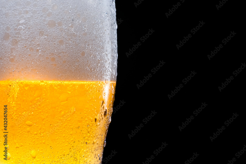 Half beer glass with beer and foam on a black background. Space for text and logo. Half beer glass with beer and foam on a black background. Space for text and logo.