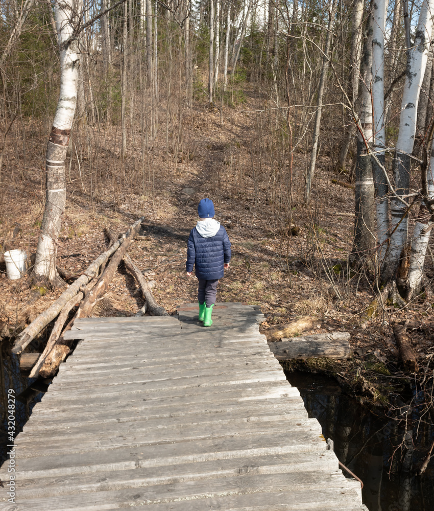 boy walks on a wooden bridge in the forest. concept of out-of-town rest and travel. boy walks on a wooden bridge in the forest. concept of out-of-town rest and travel.