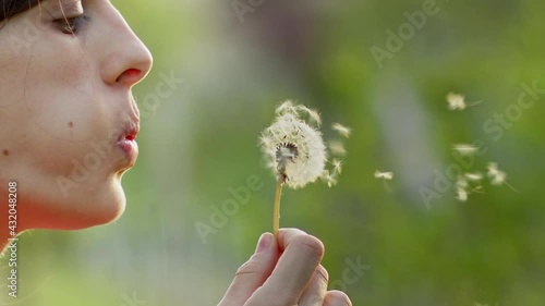 Slow motion footage of female blowing dandelion outside at sunset
