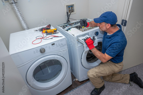 Appliance technician working on a front load washing machine in a laundry room photo