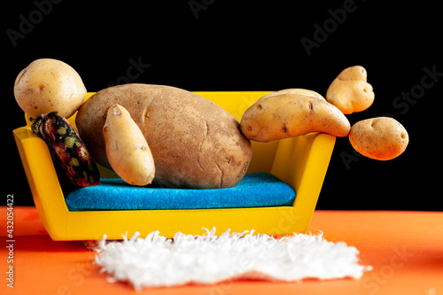 A quirky metaphorical concept image showing a potato man lying on a couch in a living room setting. Image for being couch potato, obesity, sedentary lifestyle and health effects. photo