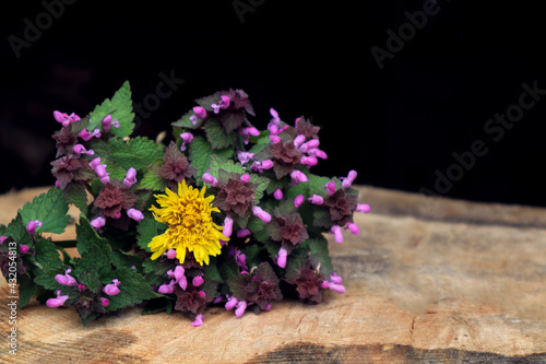 Yellow dandelion in a bouquet of wild flowers on a wooden background  close-up