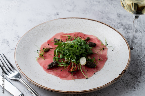 Top view of fresh tuna carpaccio, thin transparent slices, expensive italian meal