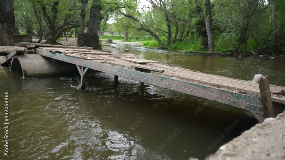 Rustic bridge over river grown by the thaw in spring Rustic bridge over river grown by the thaw in spring