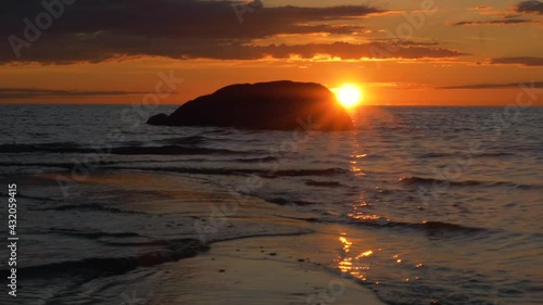 Large rock and waves moving over sand and shallow sea, summer sunset, in Scandinavia photo