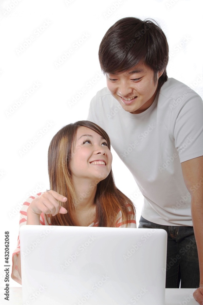 A couple of young Japanese students operating a computer A couple of young Japanese students operating a computer