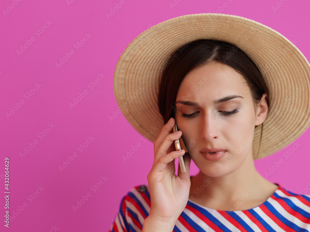 Portrait of young girl with serious face while using smartphone isolated on pink background