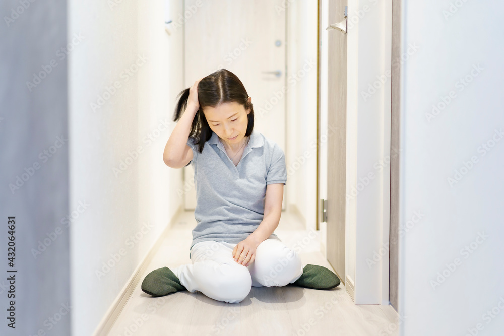 疲れて、廊下で座り込む中年女性 疲れて、廊下で座り込む中年女性
