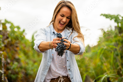 blonde woman squeezing a bunch of grapes with her hands