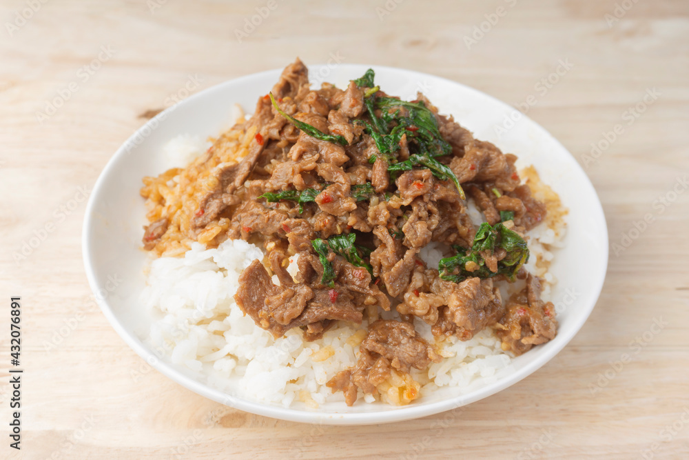 Close up Rice topped with stir-fried beef and holy basil (Pad Ka Prao) popular Thai street food. on the wooden table Close up Rice topped with stir-fried beef and holy basil (Pad Ka Prao) popular Thai street food. on the wooden table