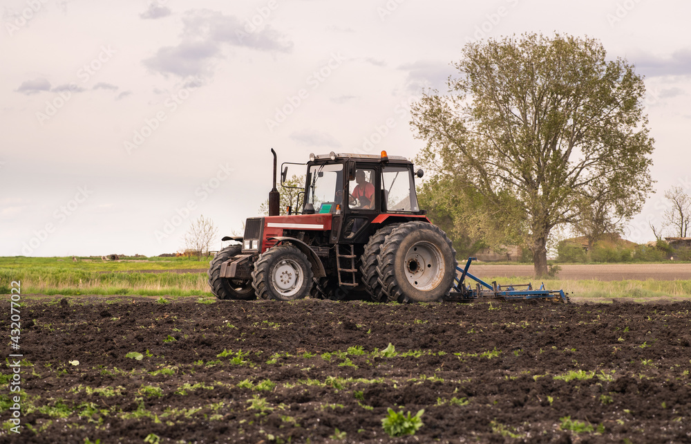Tractor is preparing the land at dusk Tractor is preparing the land at dusk