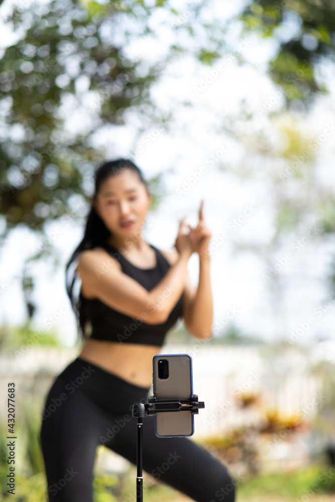 Asian sporty girls dancing with their smartphones at the park. - obrazy, fototapety, plakaty 