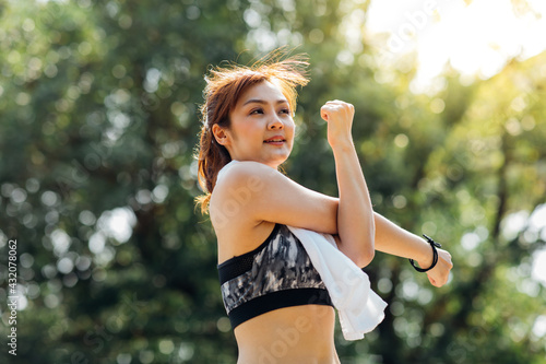 Portrait of beautiful healthy young woman warming up and exercising outdoors in the park.  stretching  arms and legs