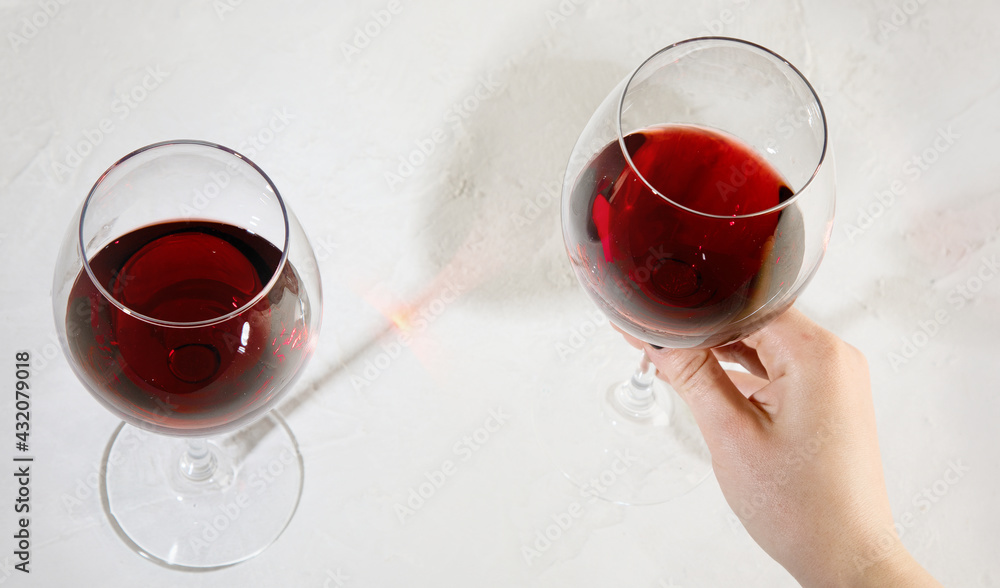 Young woman holding glass of red wine on white background. Hand with black polish. - obrazy, fototapety, plakaty 
