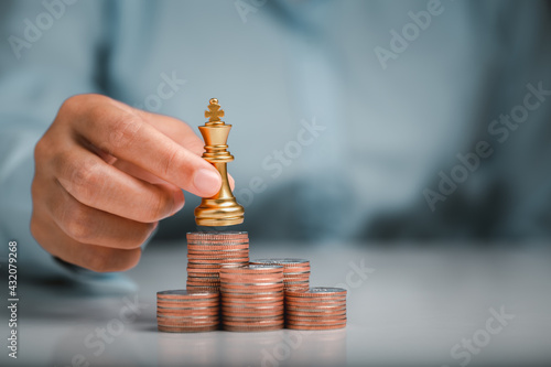 Human hand holding gold king chess on stack of coins, money power or saving money, financial growth, business finance wealth and success concept.