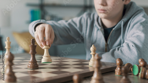 Boy playing chess and moving a piece