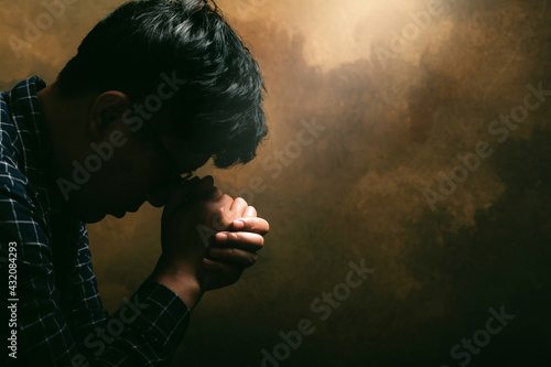 Religious man praying to God resting his chin on his hands.His hands are praying for God's blessings.