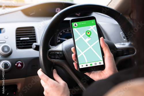 Woman sitting in front of the driver in the car Using a smartphone, look at a map, give directions and use the application to get to the destination. Black car steering wheel handle.