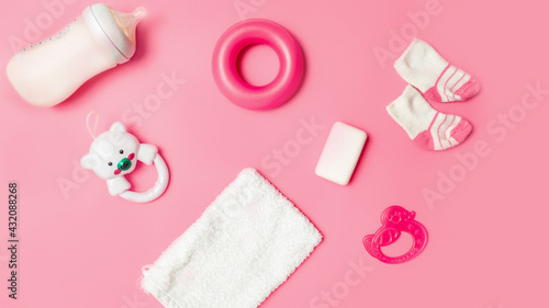 Top view of baby accessories with toy rattle on pink table background. A Girl Baby Shower. Mock up