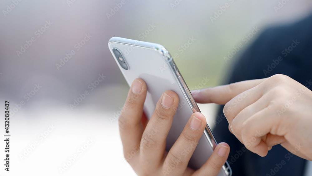 屋外でスマートフォンを操作するマスク姿のビジネスウーマン 屋外でスマートフォンを操作するマスク姿のビジネスウーマン