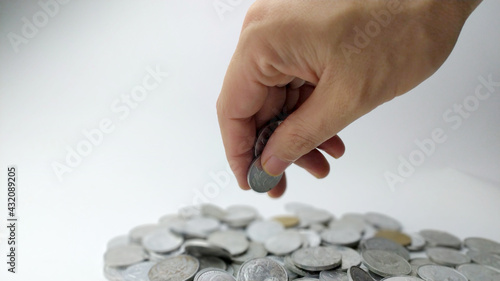 Hand hold coin on pile of coins on white background