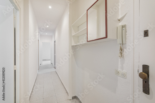 White empty corridor with doors and floor tiles in an old apartment