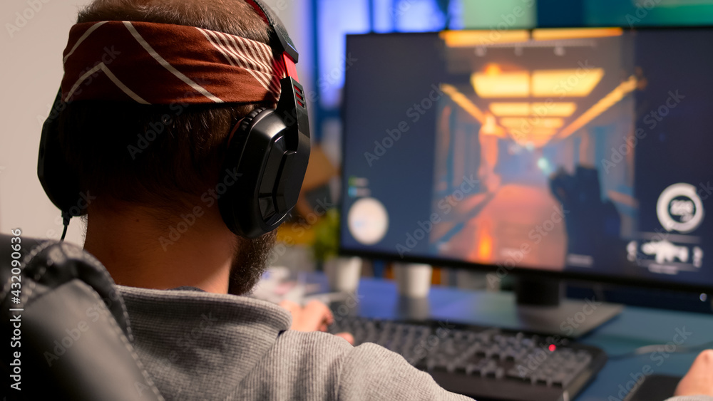 Pro gamer playing on powerful computer first person shooter video game during live championship, wearing headphones. Competitive player streaming video game tournament using professional equipment Pro gamer playing on powerful computer first person shooter video game during live championship, wearing headphones. Competitive player streaming video game tournament using professional equipment