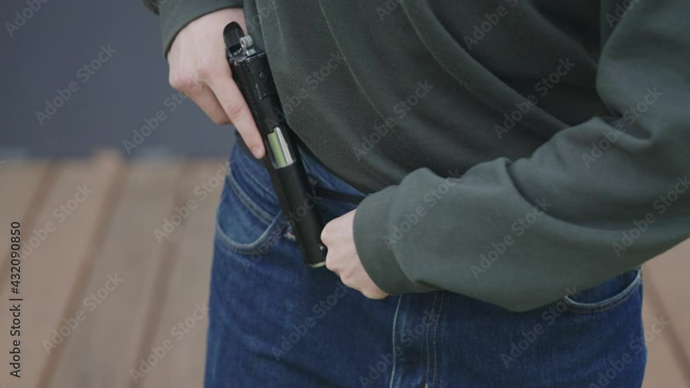 The man is hiding the gun in his pants. Illegal carrying of firearms The man is hiding the gun in his pants. Illegal carrying of firearms