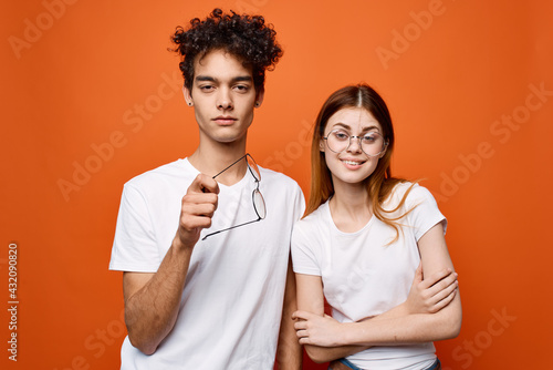 cheerful young couple in white t-shirts emotions communication orange background
