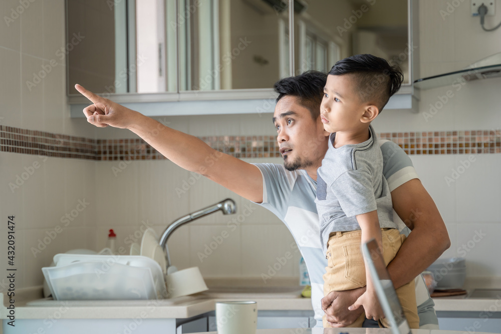 Father or dad holding son distracting him to look at the window Father or dad holding son distracting him to look at the window
