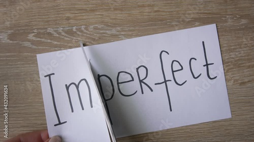 Female hands cut paper with written IMPERFECT word to turn it into PERFECT. Close up