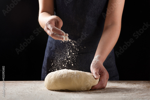 фотографія Cook hands kneading dough, sprinkling piece of dough with white wheat flour