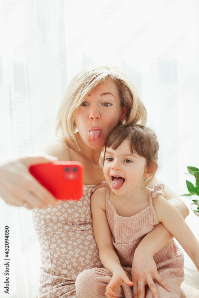 Cute little girl and her young mother fooling around, taking selfies Cute little girl and her young mother fooling around, taking selfies