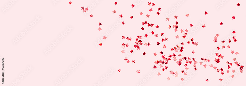 scattered pink holographic glitter confetti star shaped on candy pink background top view copy space. Festive holiday pastel backdrop. Birthday, giveaway, Christmas, New Year. Mothers Day banner