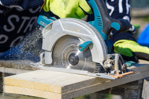 Obraz na płótnie Carpenter working with a circular saw outside in sunny day