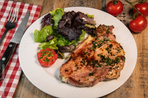 Recipe for grilled pork chop, maple syrup and fresh cilantro marinade, parsley, garlic, served with a salad.