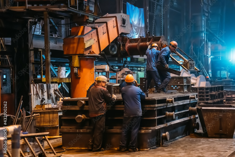 Obraz premium Workers in process of work with large mold iron cast on steel mill foundry.