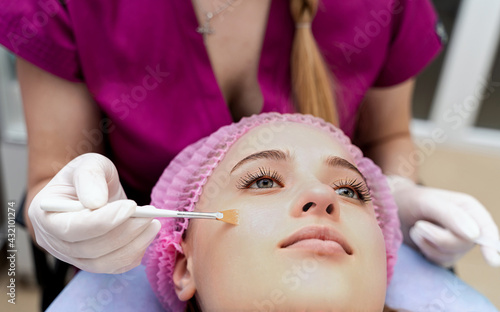 Professional cosmetologist doing face care in gloves. Female patient lying and relaxing.