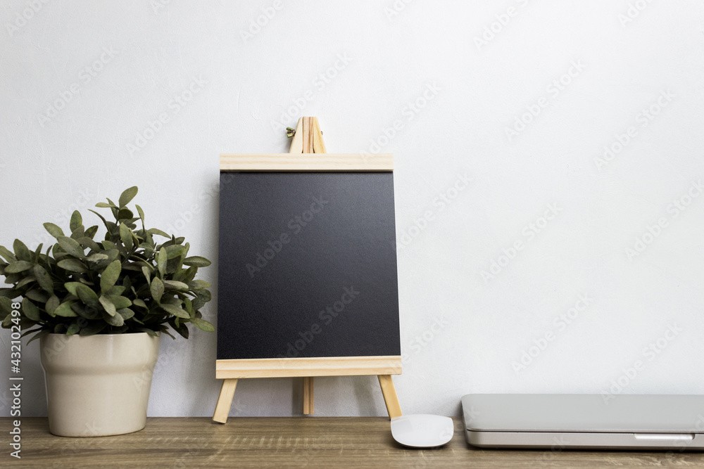 A mock up computer device with mouse, black note on table. 