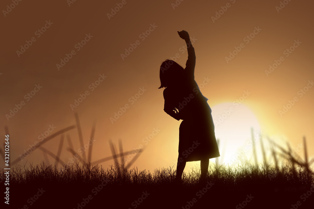 Silhouette of little girl with backpack with happy expression with sunset background