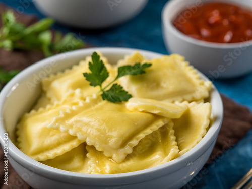 Homemade ravioli or dumplings with sauce and ketchup on a blue table. Recipes