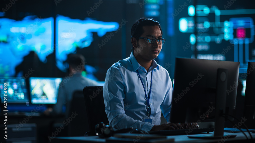 Professional IT Technical Support Specialist and Software Developer Working on Computer in Monitoring Control Room with Digital Screens with Server Data, Blockchain Network and Surveillance Maps. Professional IT Technical Support Specialist and Software Developer Working on Computer in Monitoring Control Room with Digital Screens with Server Data, Blockchain Network and Surveillance Maps.