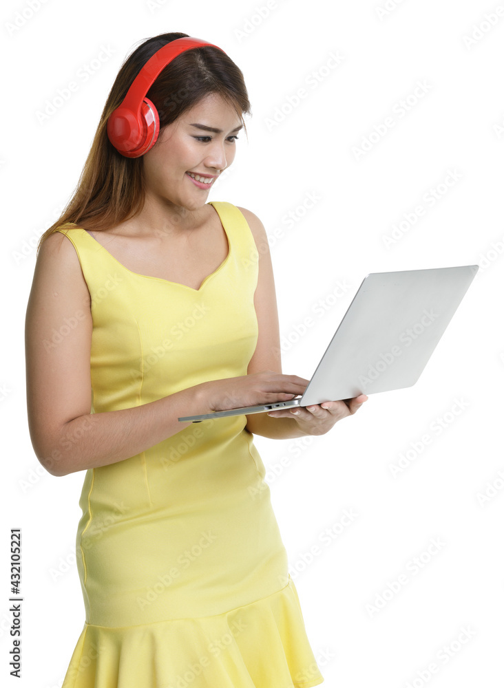 Isolated portrait close up shot of Asian happy female teenager wear large red headphones stand smiling look at screen hold laptop computer in hand listening to music Isolated portrait close up shot of Asian happy female teenager wear large red headphones stand smiling look at screen hold laptop computer in hand listening to music