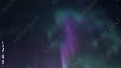 Beautiful straight Aurora Borealis - bright green magenta and purple vertical light stripes on clear without clouds starry black night sky. A lot of real stars seen in Northern hemisphere, cold winter